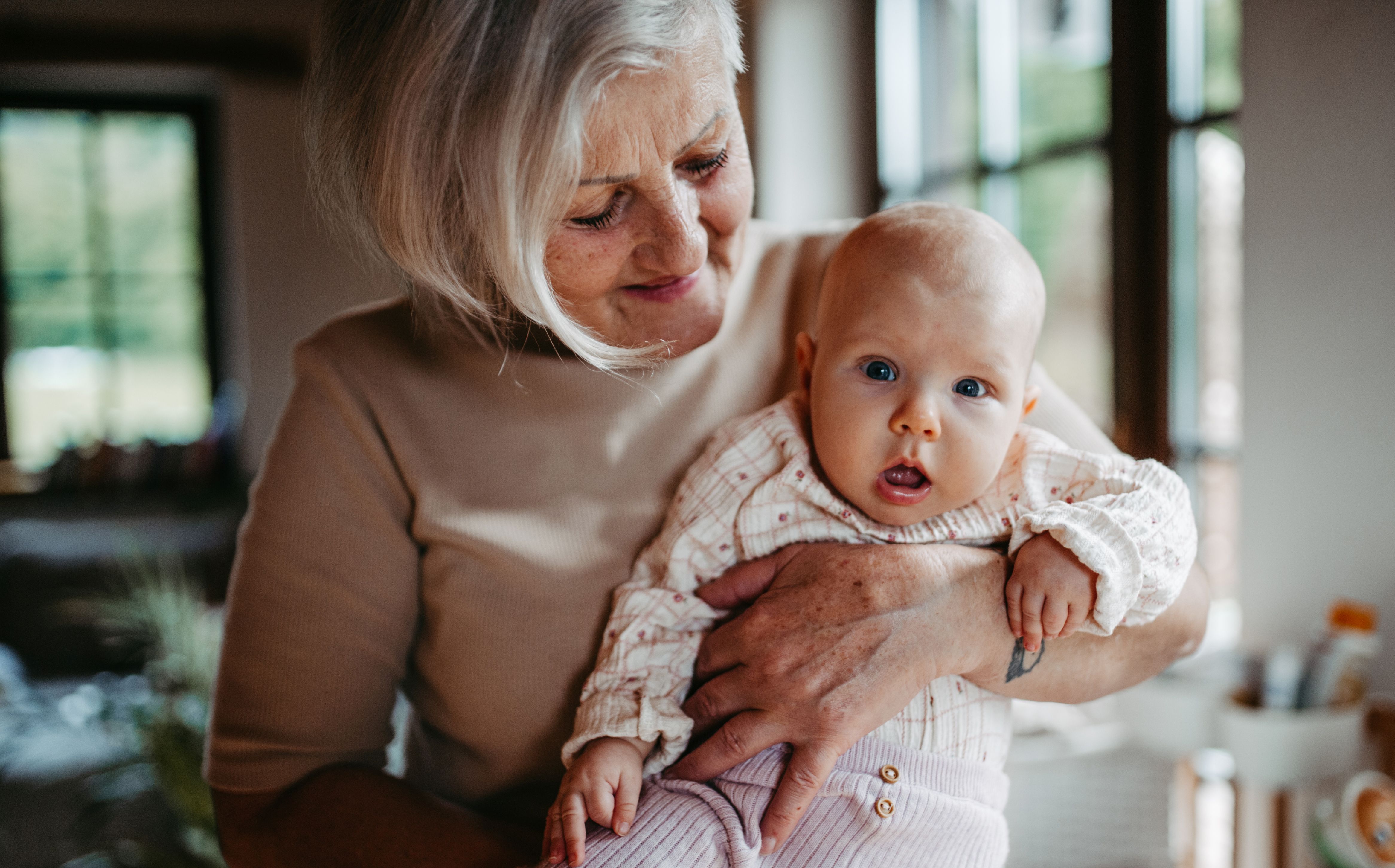 Eine ältere Frau hält ein Baby im Arm 